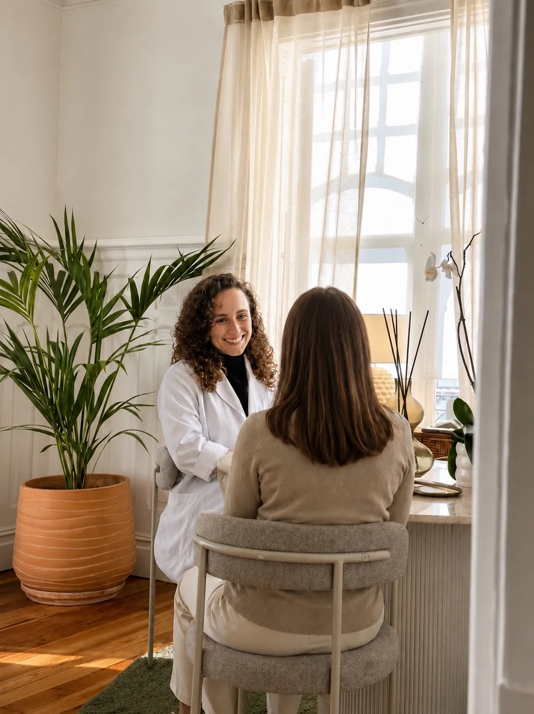 Médica sonriente atendiendo a una paciente en una consulta luminosa de la clínica